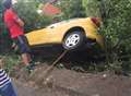 Woman trapped in car wedged between trees on steep bank