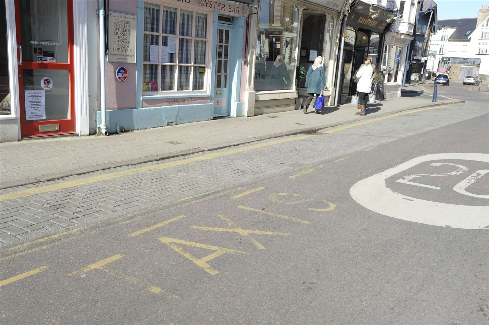 The taxi rank, sign, and faded road markings outside Samphire, High Street, Whitstable.