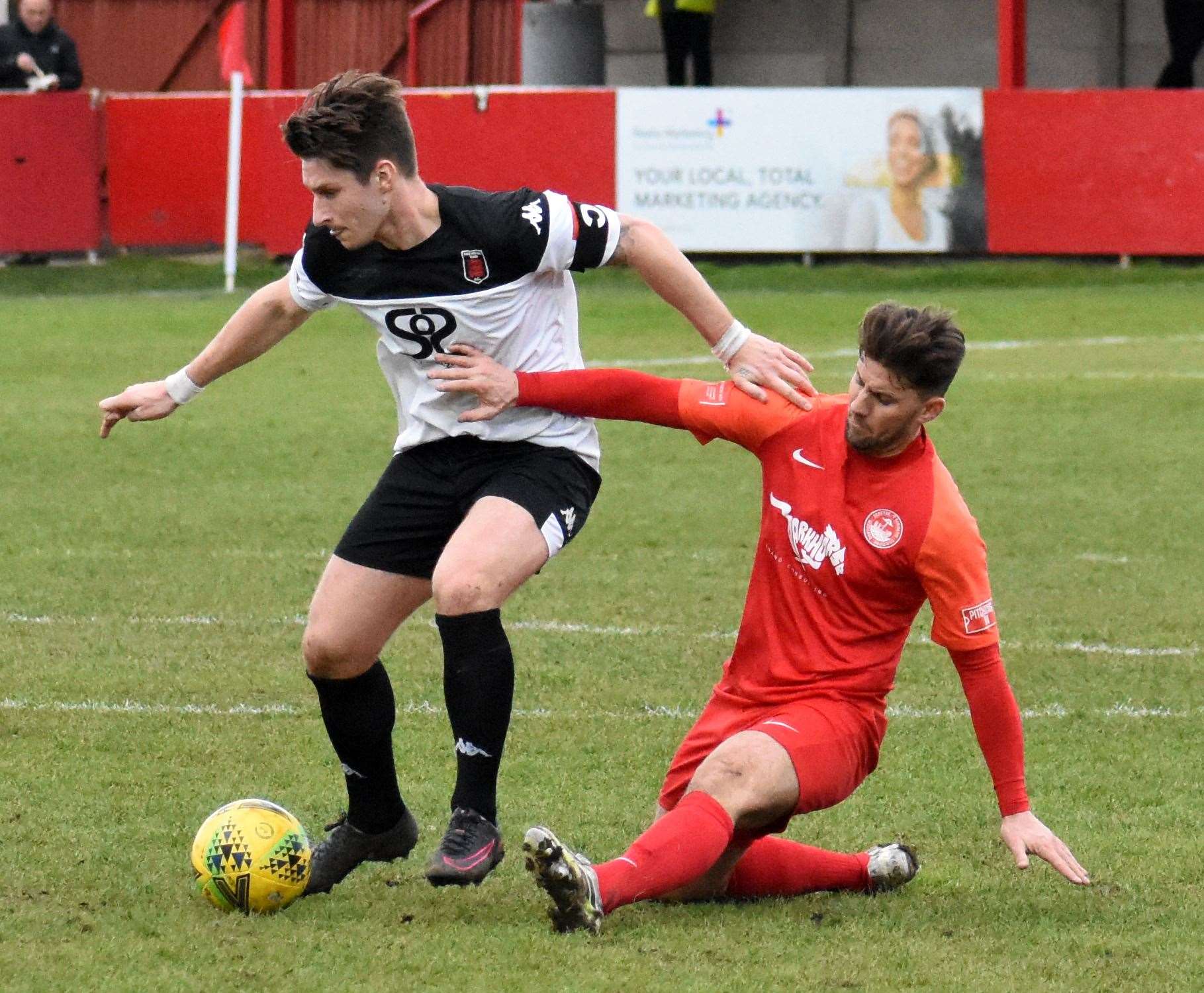 Faversham captain Harry Harding tries to evade the challenge of Hythe player-coach James Rogers during Town's 2-1 defeat at Reachfields. Picture: Randolph File