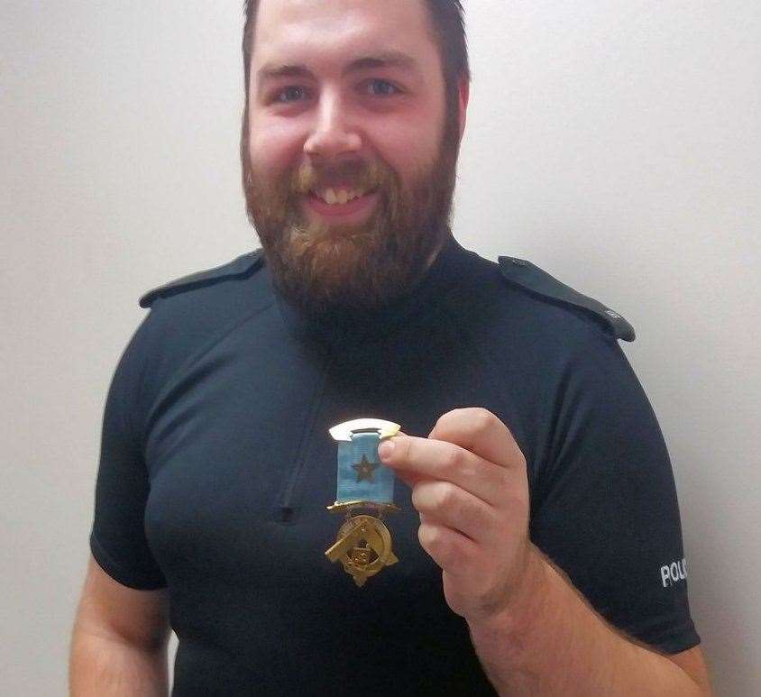 PC Alex Dyer holding the stolen medal. Picture: Kent Police