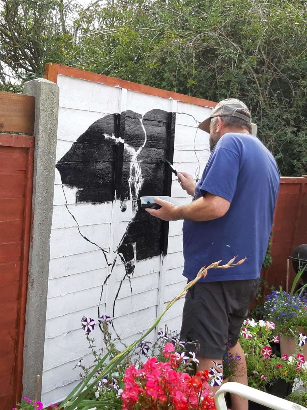 Ron Williams hard at work painting a fence panel in his Walderslade garden