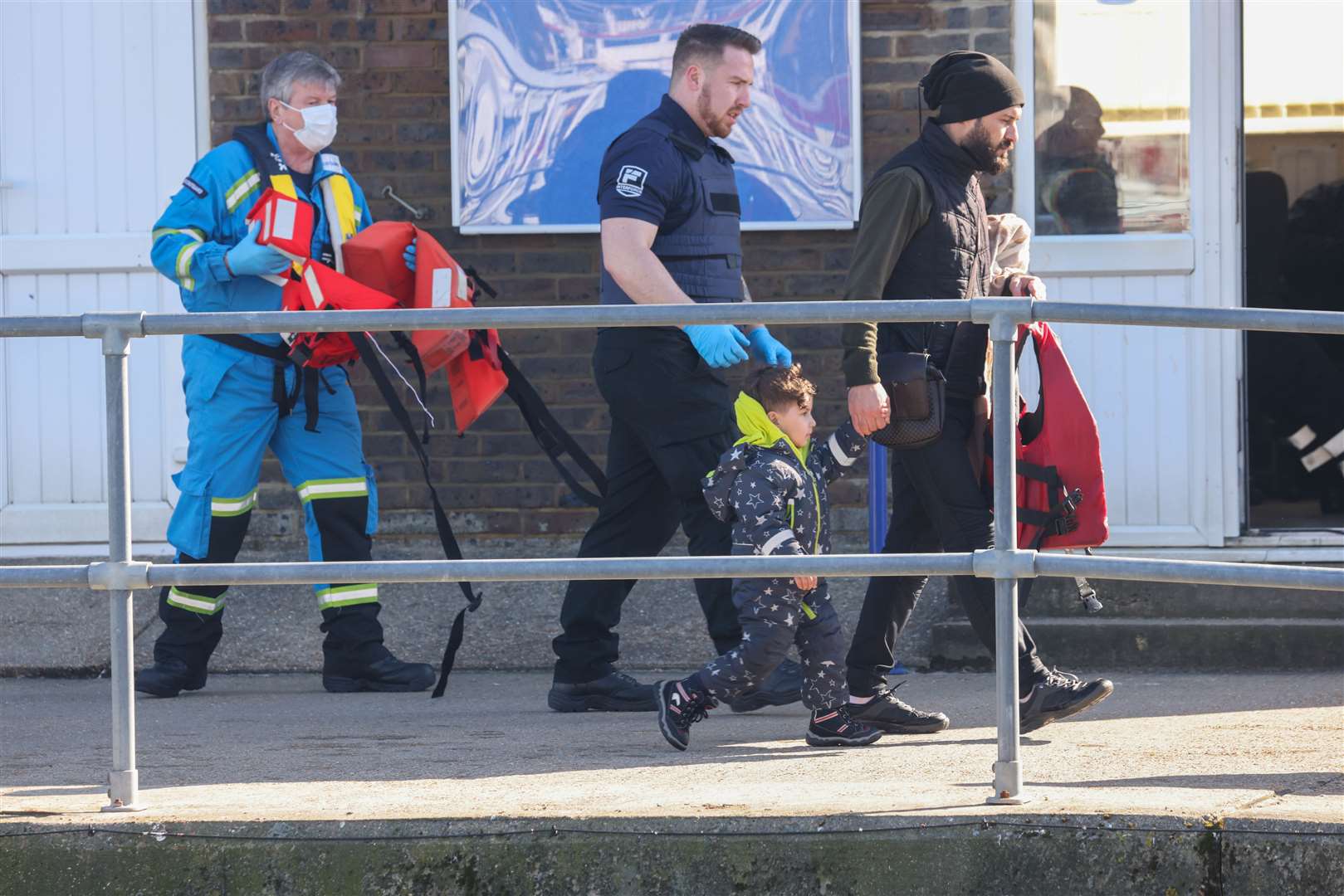 Another child holds the hand of an adult and is escorted to safety by an official Picture: UKNIP
