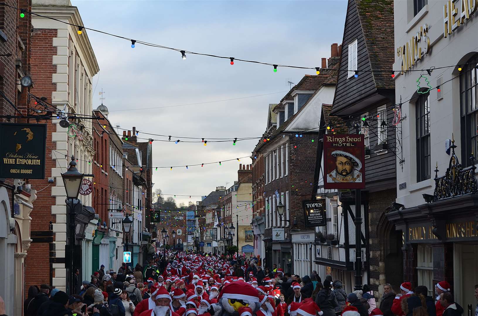 People clad in red and white make their way down Rochester's High Street during the mammoth Santa run [credit: Jason Arthur]