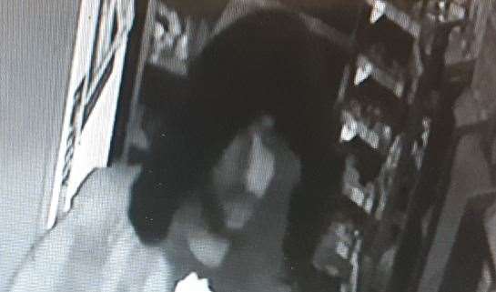 A hooded figure captured on camera inside the shop