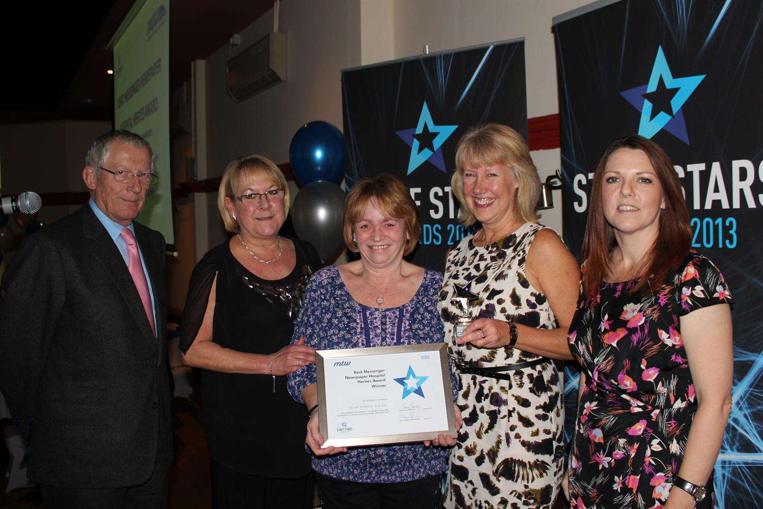 The team who work with consultant Russell Burcombe at the Kent Oncology Centre at Maidstone Hospital receive their KM award last year from editor Denise Eaton (right) and Nick Hewer from the Apprentice