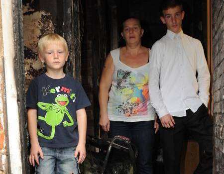 Dane Tolhurst-Young, mum Sally and brother Robert with the fire damage in Dartford