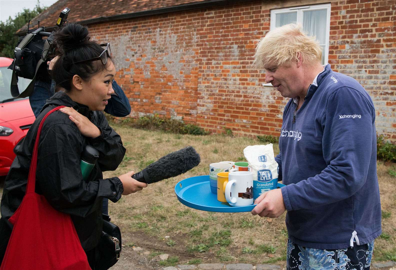 Boris Johnson brings tea for the press to drink outside his house in Thame in August 2018 (Aaron Chown/PA)