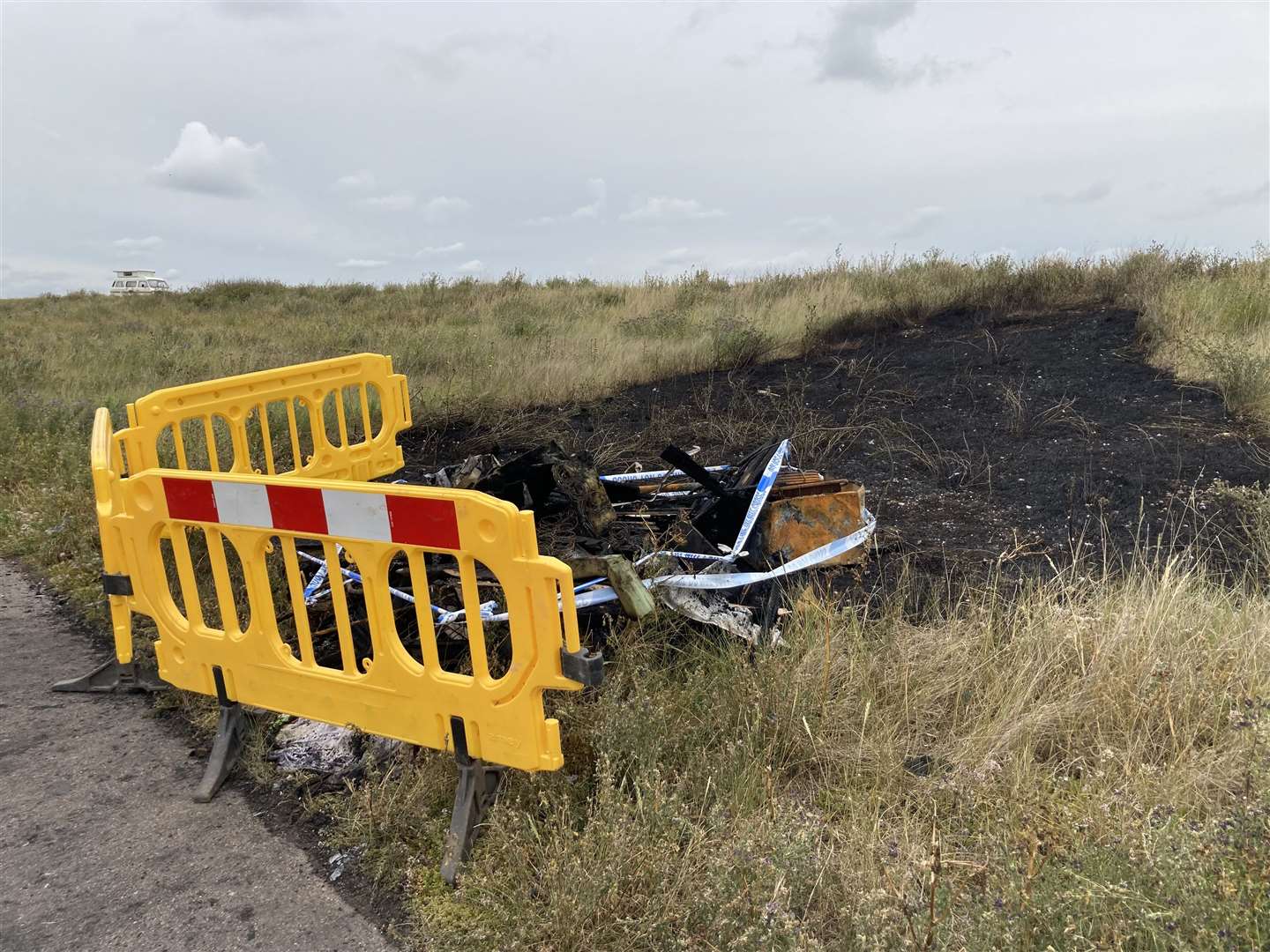 Barriers cordon off the charred remains of a motorhome