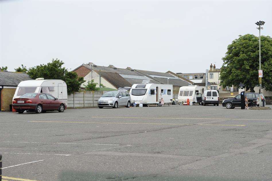 Eight caravans are parked around the perimeter wall of the car park