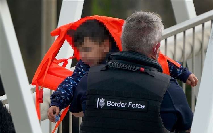 A Border Force officer carries a young child from a boat in Dover. Picture: Gareth Fuller/PA