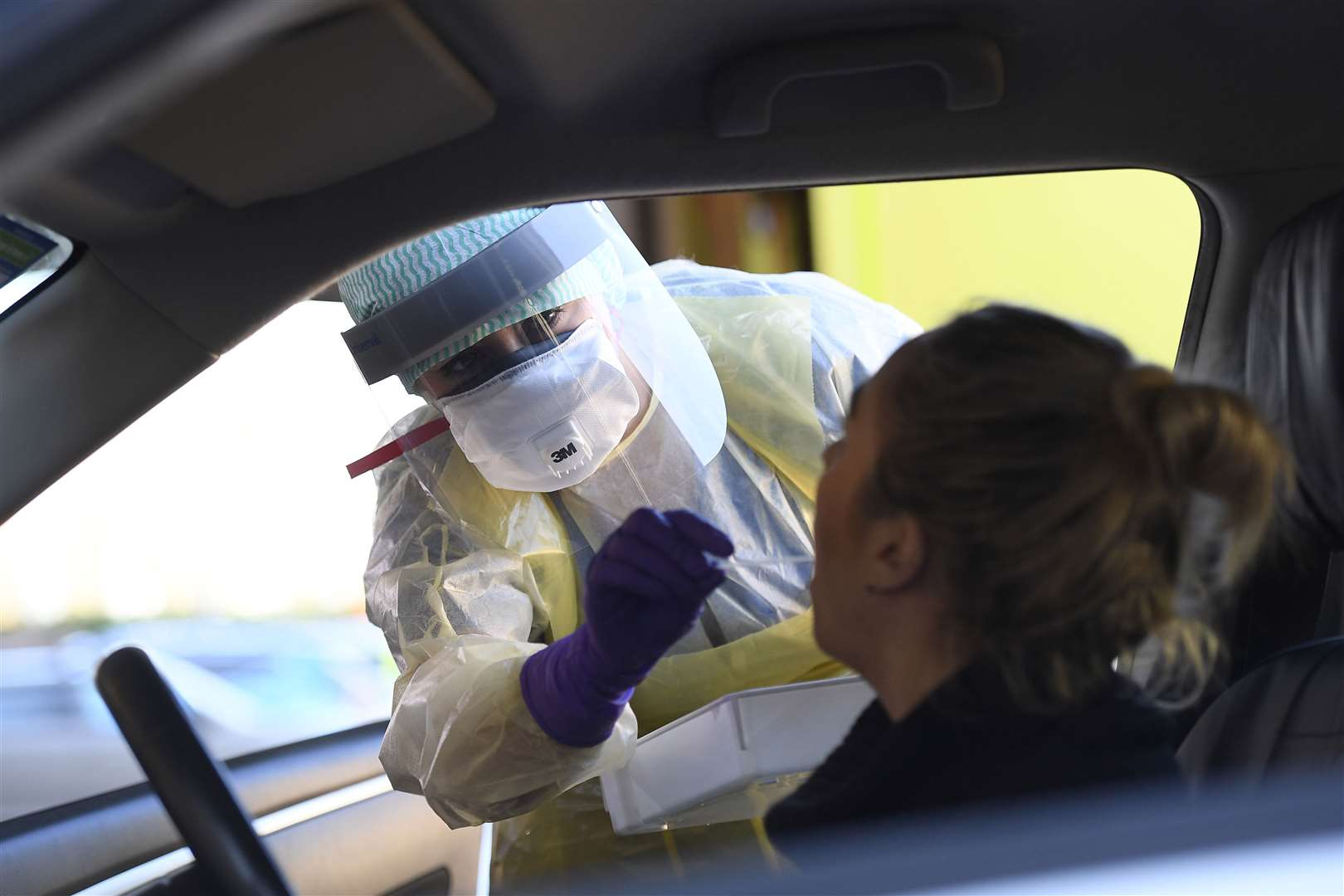 An emergency department nurse at Antrim Area Hospital, Co Antrim, in Northern Ireland swabs a woman at a drive-in coronavirus testing site (Michael Cooper/PA)