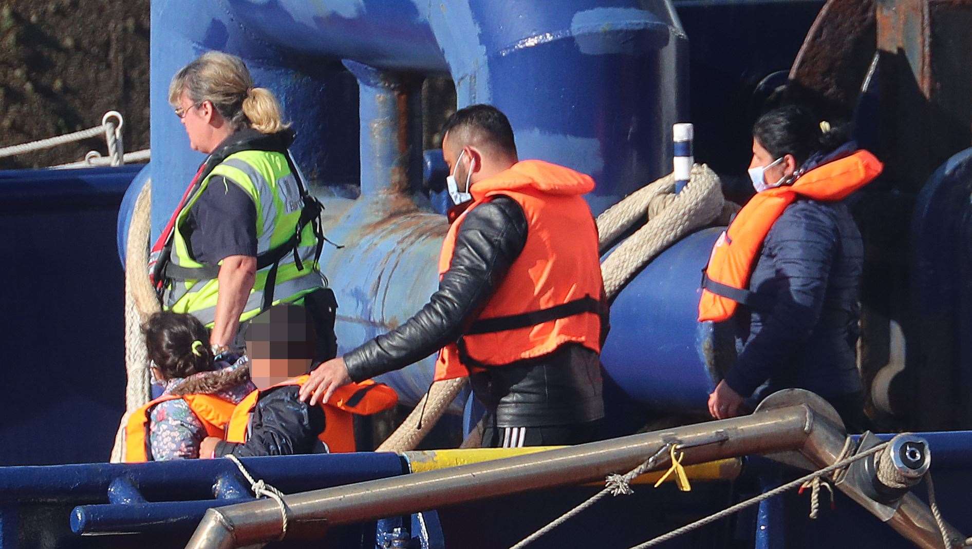 A Border Force officer escorts a young family thought to be migrants from a Border Force vessel after they were brought into Dover, Kent (Gareth Fuller/PA)