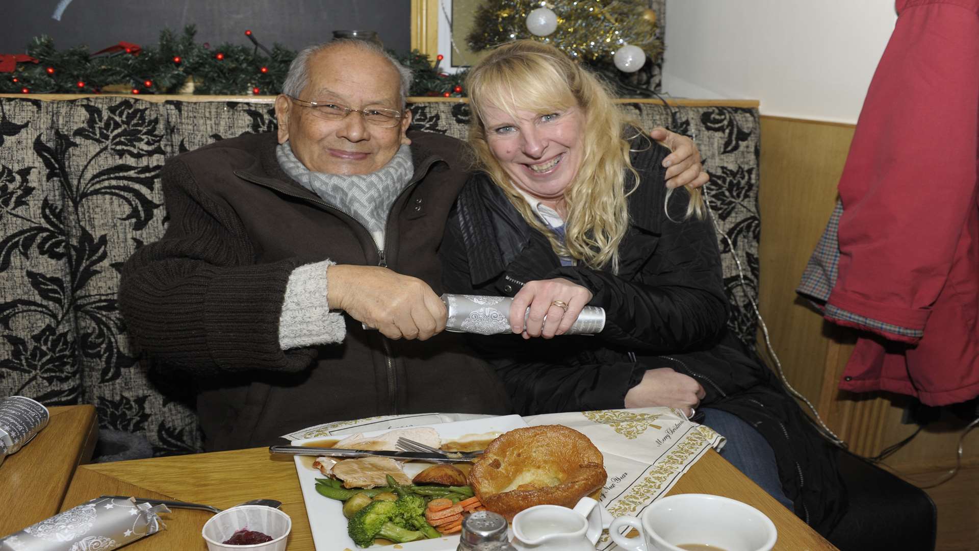 Ron Valense pulls a cracker with Louise Collins from the Thanet Volunteer Bureau at The Hoy free Christmas dinner event
