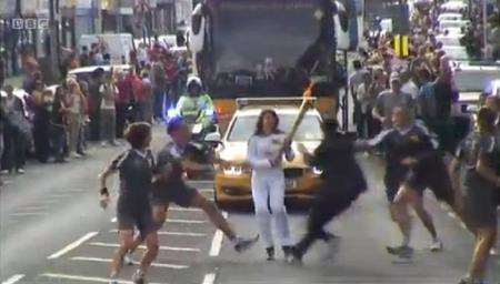 A spectator attempts to grab the Olympic flame from torchbearer Anna Skora in Gravesend. Picture: BBC