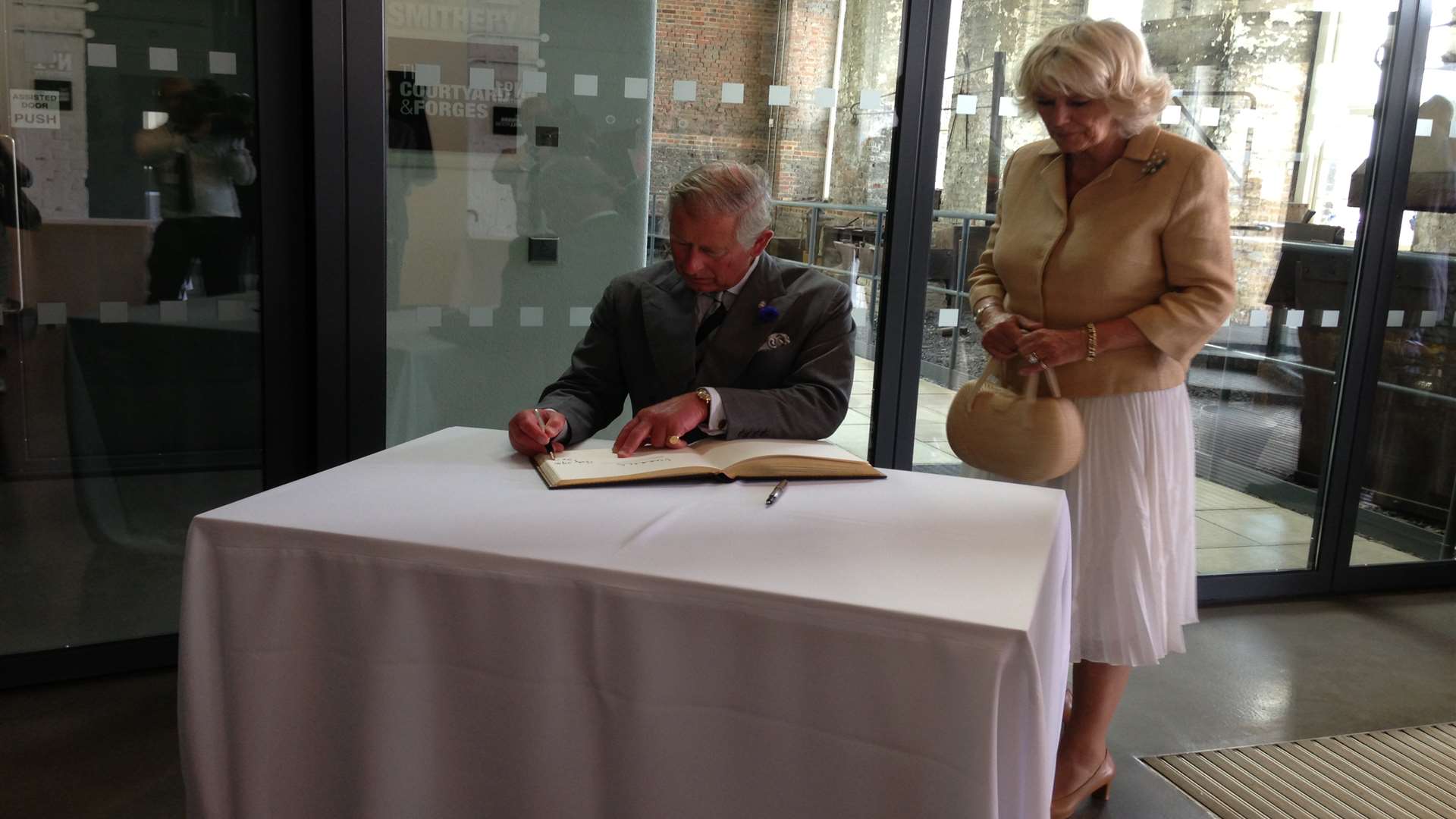 Prince Charles and the Duchess of Cornwall sign the visitors' book at Chatham Historic Dockyard