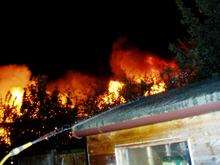 A neighbour damps down an outbuilding as the fire rages just metres away - picture supplied by 'Minster Matters' magazine