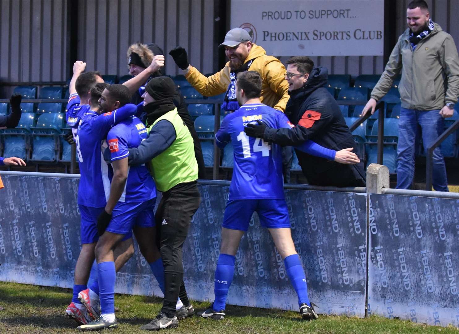 Herne Bay’s players and fans celebrate a Michael Salako goal in their 2-0 weekend win at Phoenix Sports. Picture: Alan Coomes