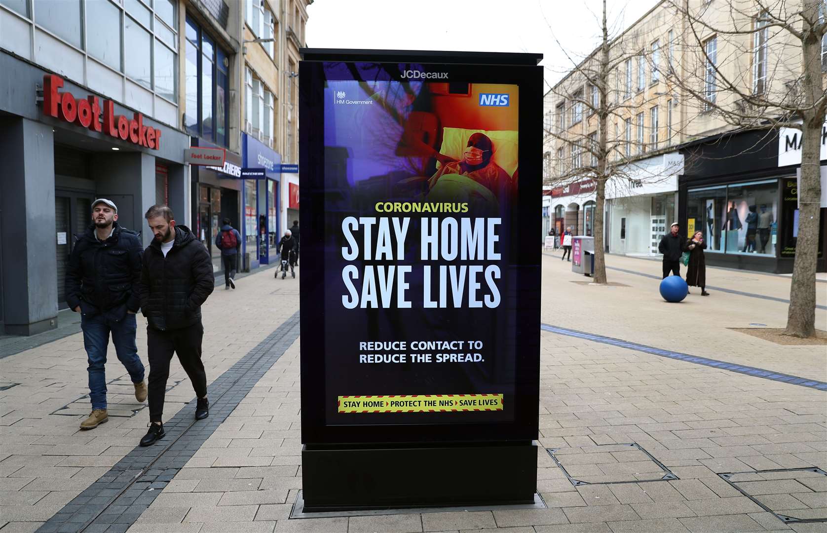 People walk past a ‘Stay Home Save Lives’ sign on Broadmead in Bristol during England’s third national lockdown to curb the spread of coronavirus (Andrew Matthews/PA)