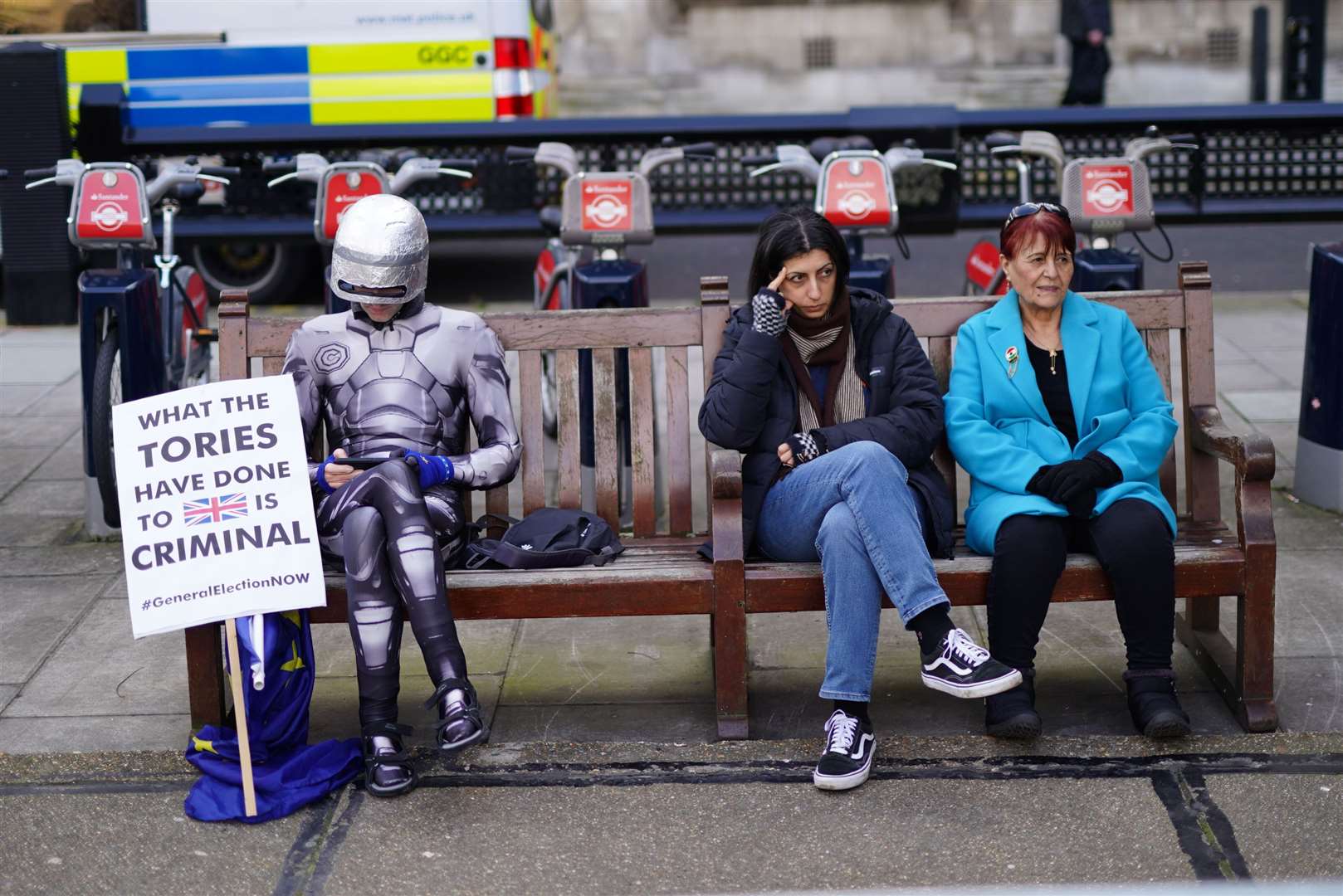A protester dressed as RoboCop sits on a bench near the Palace of Westminster, as the Chancellor delivers his Budget to Parliament (Jordan PettittPA)