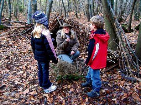 Natural Pathways instructor Hannah Nicholls teaches Rebecca and Bryn Scholefield in the woods.