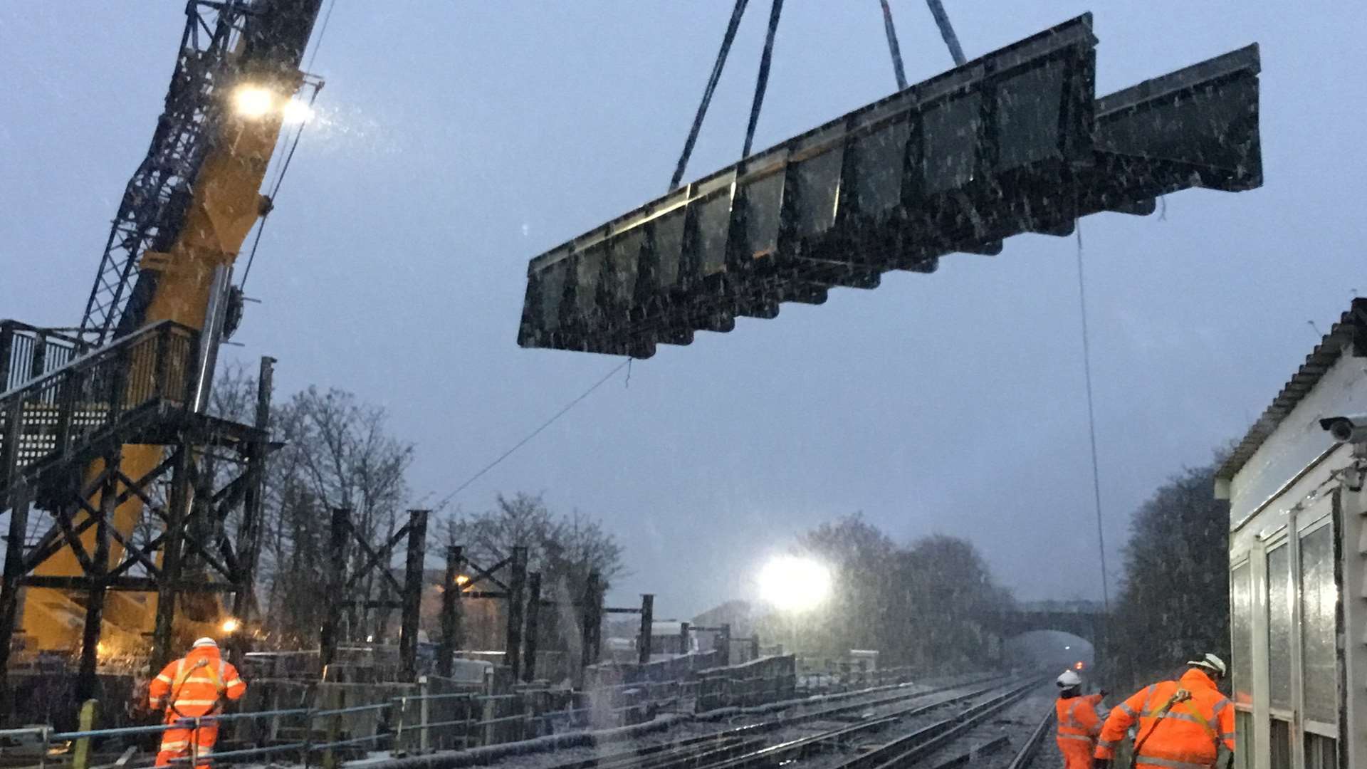 Stone Crossing railway station's new footbridge is lowered into place during an early morning snowstorm