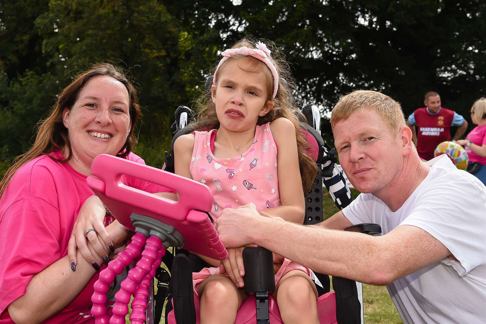 Teagan with her parents Emma and Lee at a fun day to raise money for her medication