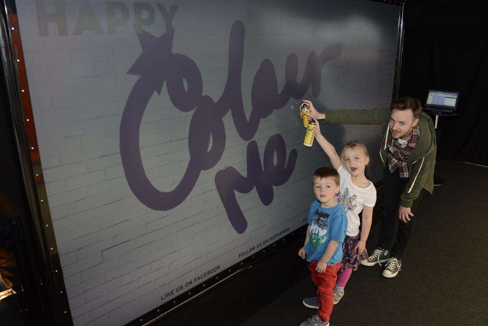 Artist Dan Hughes shows Chloe and Max Taylor how to use the Digital Graffiti Wall