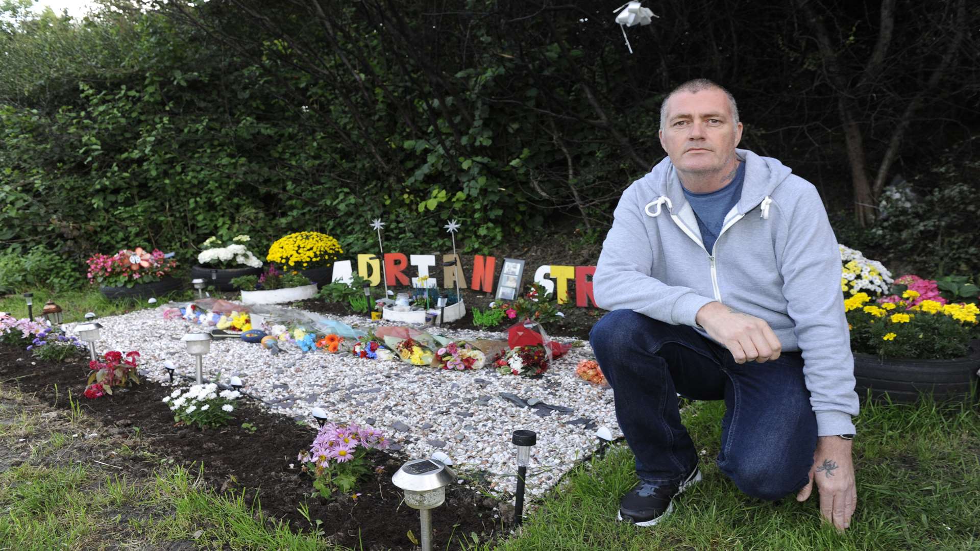 Adrian's father Andy Stroud pictured by a roadside memorial to his son last year