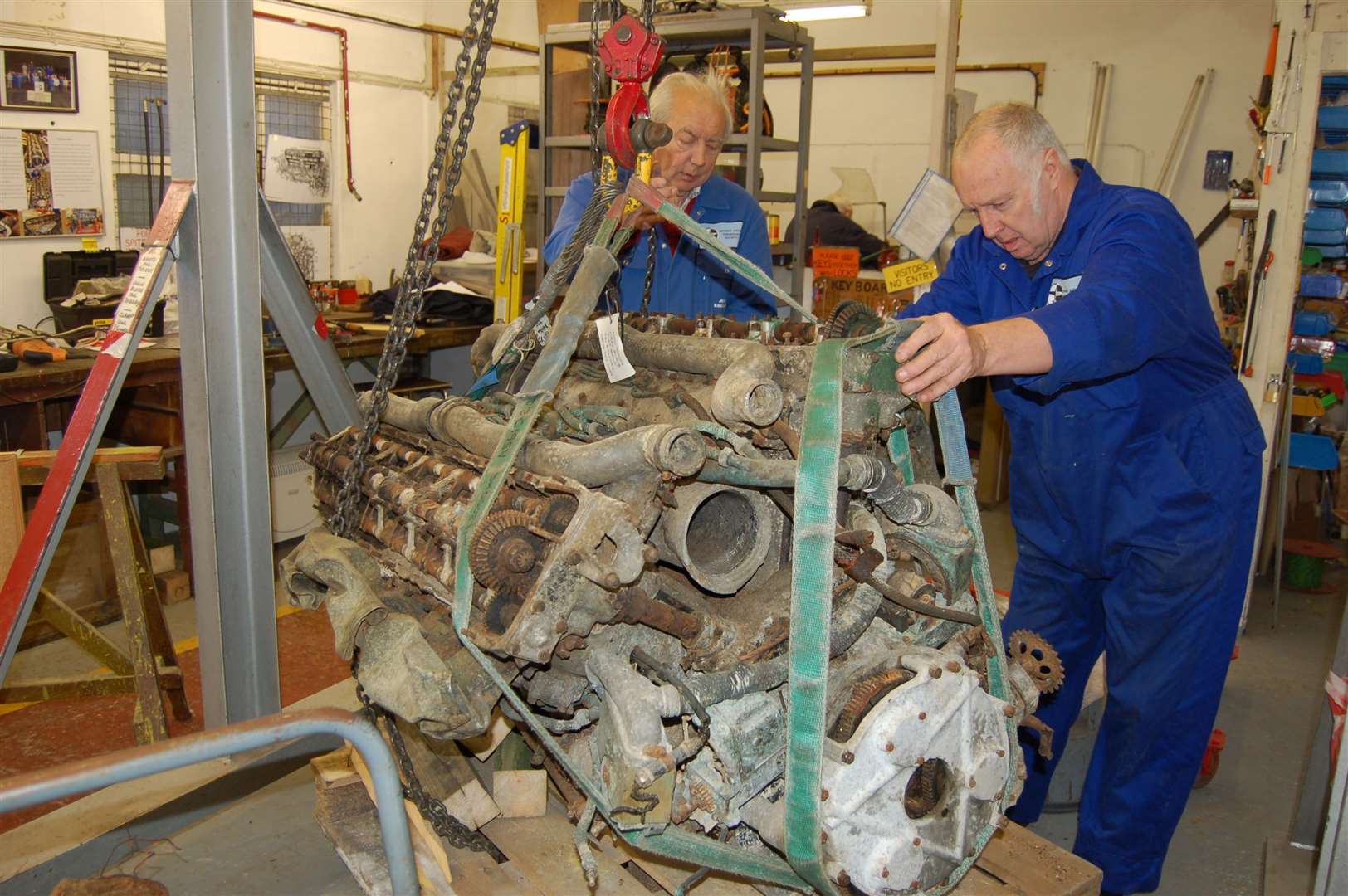 Volunteers manoeuvre a historic Merlin engine into position