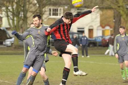 An Addisham (red) player goes up for a header against an opponent from Market Inn
