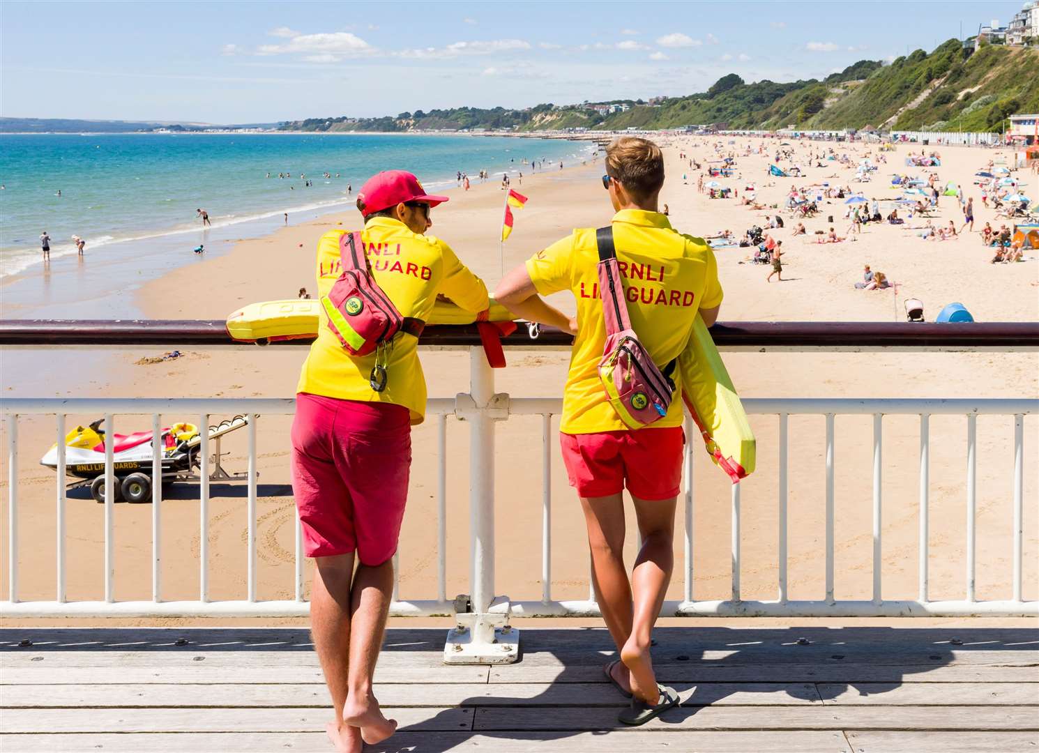 Two RNLI lifeguards in uniform watch over Bournemouth beach – the charity’s lifeguarding service launched in 2001. Image: iStock.