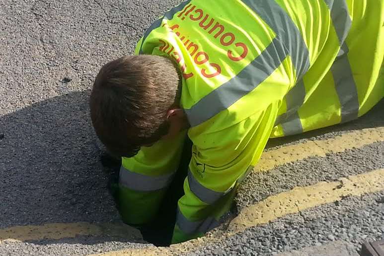 A workman examines the hole
