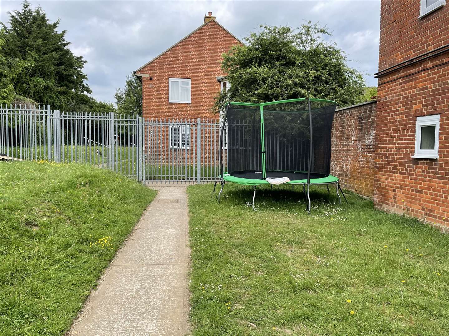 One trampoline is near to the building but the path and gate remain clear