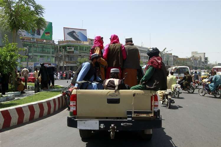 Taliban fighters sit on the back of a vehicle in the city of Herat, west of Kabul (Hamed Sarfarazi/AP)