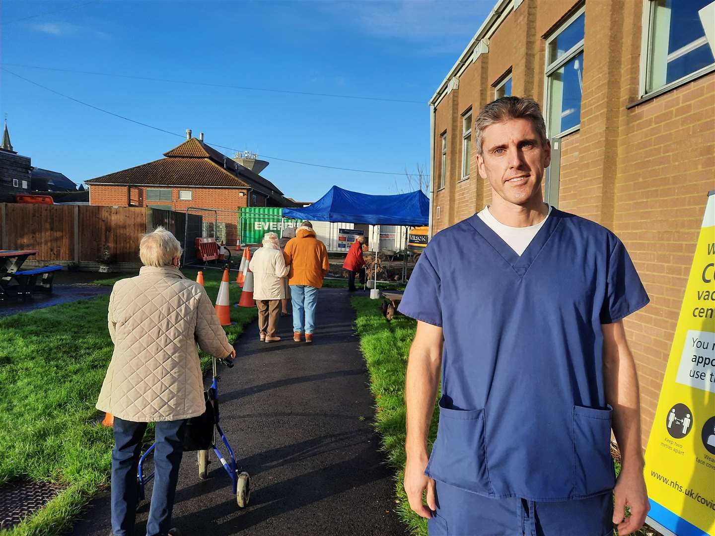 Dr Jeremy Carter stood next to a queue of people waiting for the first batch of vaccines earlier this month