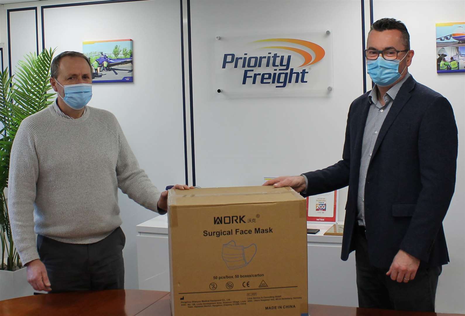 Neal Williams of Priority Freight, right,hands the masks to Noel Beamish of Dover Outreach. Picture: Priority Freight