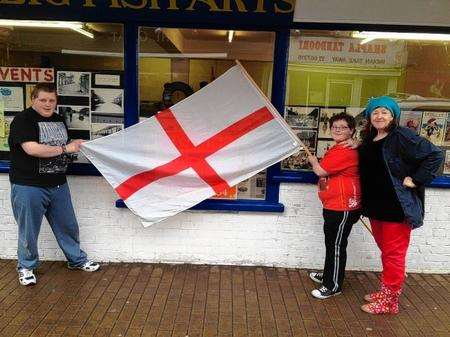 Visitors Tommy, 15, and Jackie Cleggett, 10, fly the flag with Chris Reed outside the Big Fish Arts shop