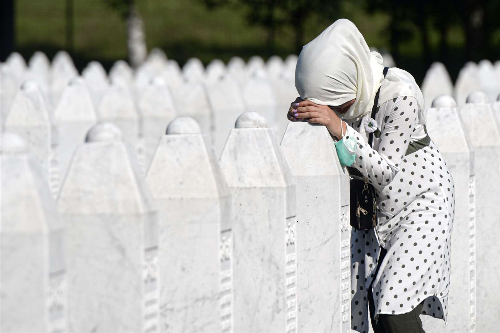 A woman leans on a grave stone in Potocari, near Srebrenica (Kemal Softic/AP)