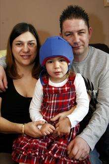 Maria and Simon Johnson with Milly who has to wear a helmet to protect her head