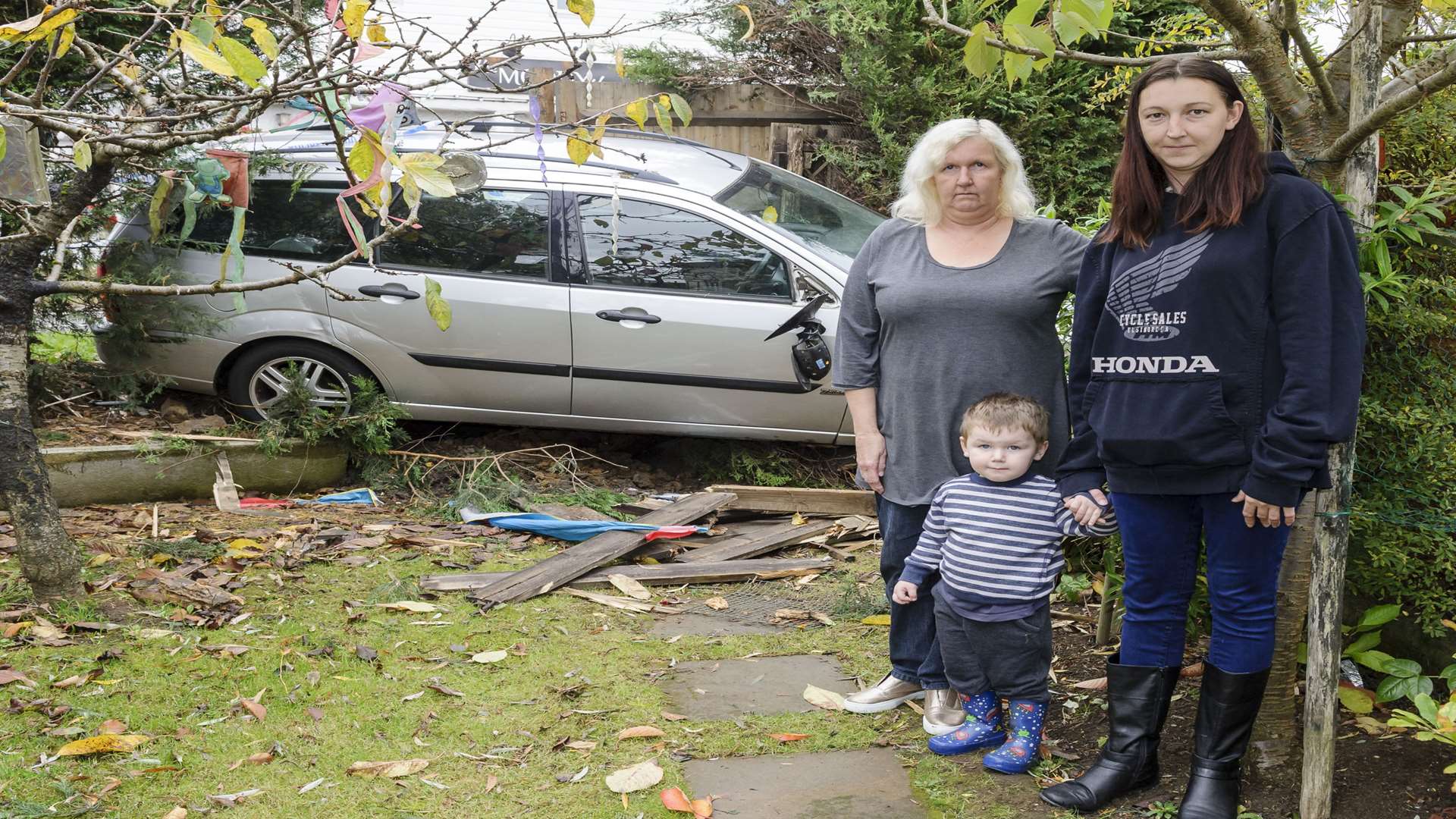 Sarah-Jane Berwick, grandson Riley Atkinson and daughter Lucy Ross with the wreckage of the car