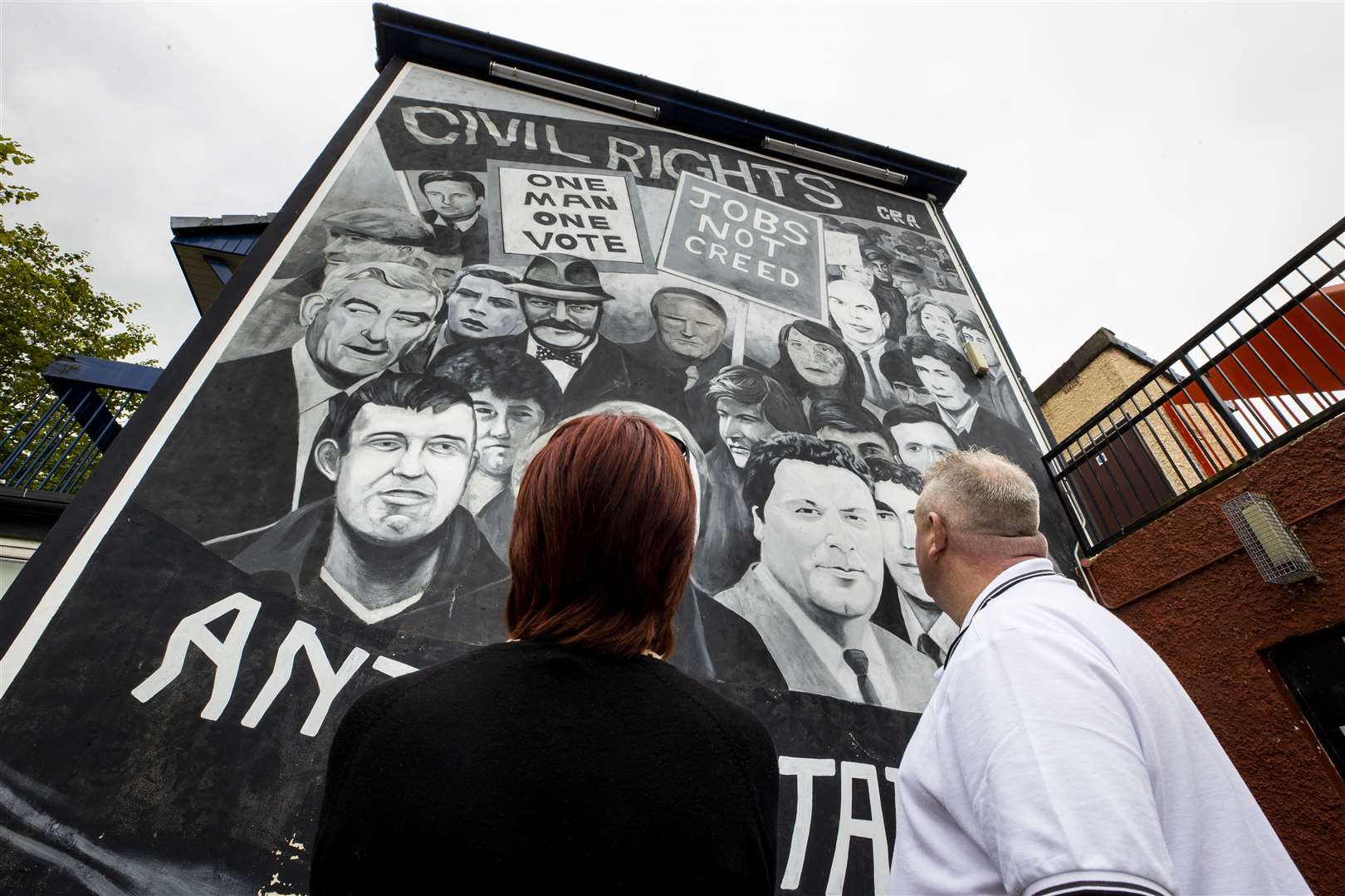 A couple look at a mural in the Bogside of Derry City that shows John Hume and others important figures from the civil rights era (Liam McBurney/PA)