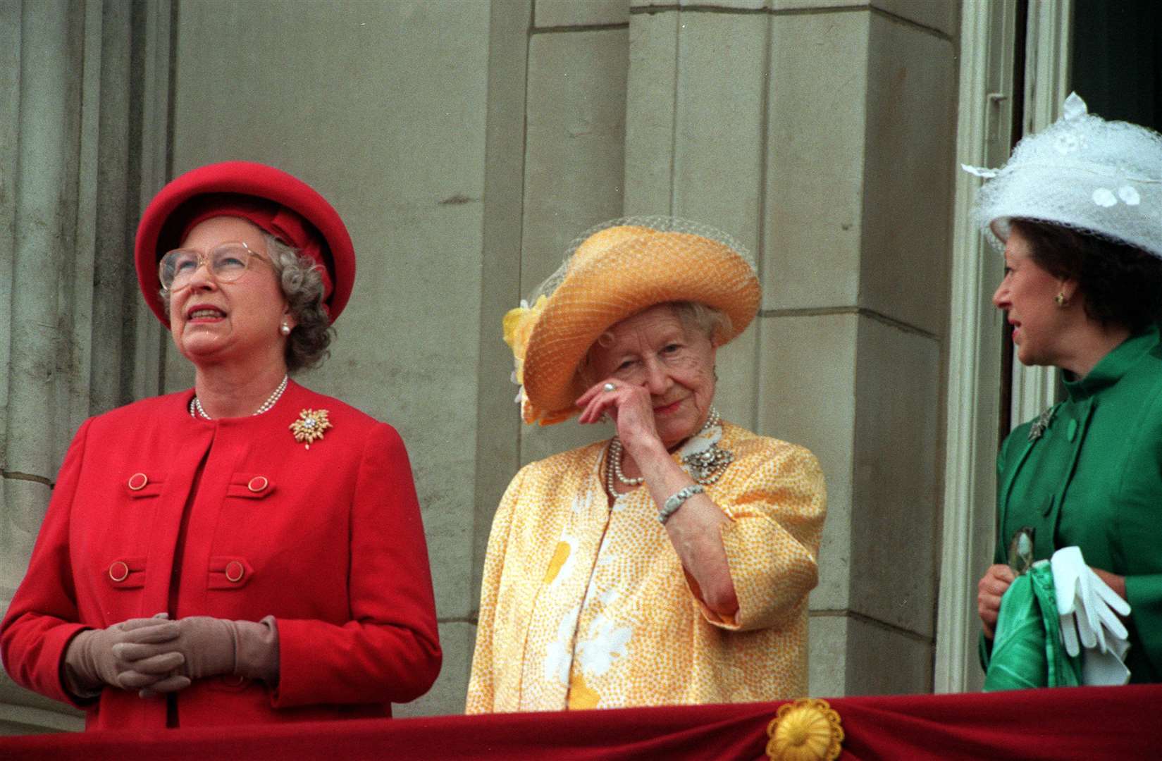 The Queen Mother, alongside the Queen and Princess Margaret, wipes her eye as she stands on the balcony of Buckingham Palace on the 50th anniversary of VE Day in 1995 (PA)