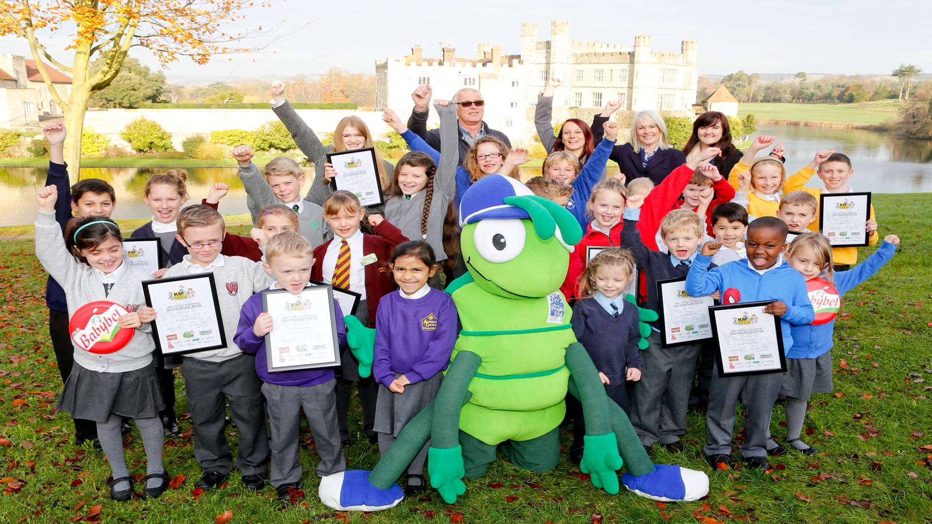 KM Walk to School Challenge Day presentations at Leeds Castle with key partners Hannah Lawrence from Leeds Castle, Paul Binnie from Medway Council, Amy Woods from Three R's Teacher Recruitment, Sara Williams from Specsavers and Catherine Underdown from KCC with pupils and mascot Buster Bug