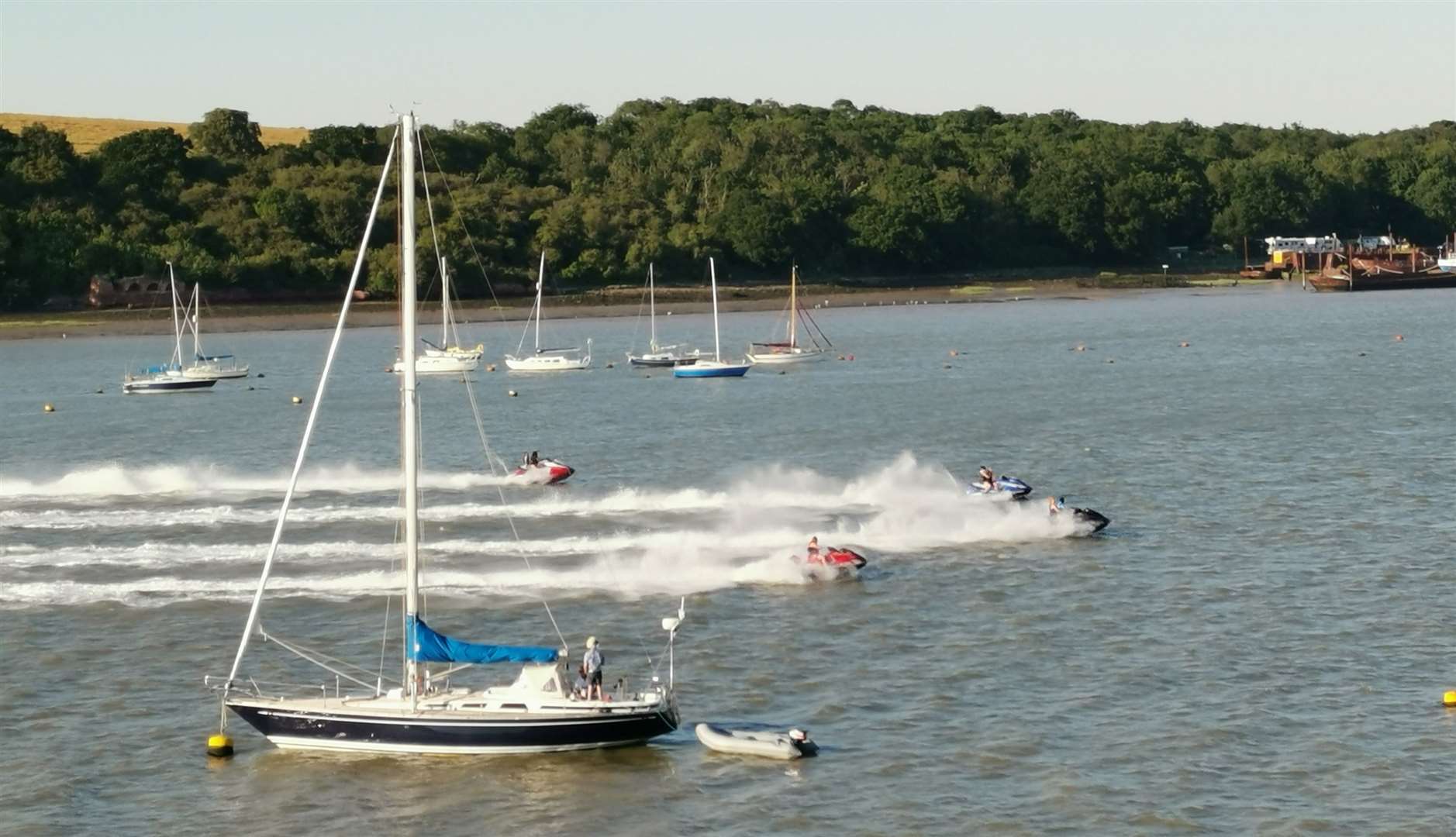 Photo of jet skiers speeding past moored boats on the River Medway