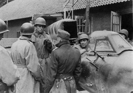 An American soldier trying out the rocket's cockpit as the German base commander faces questioning in 1945