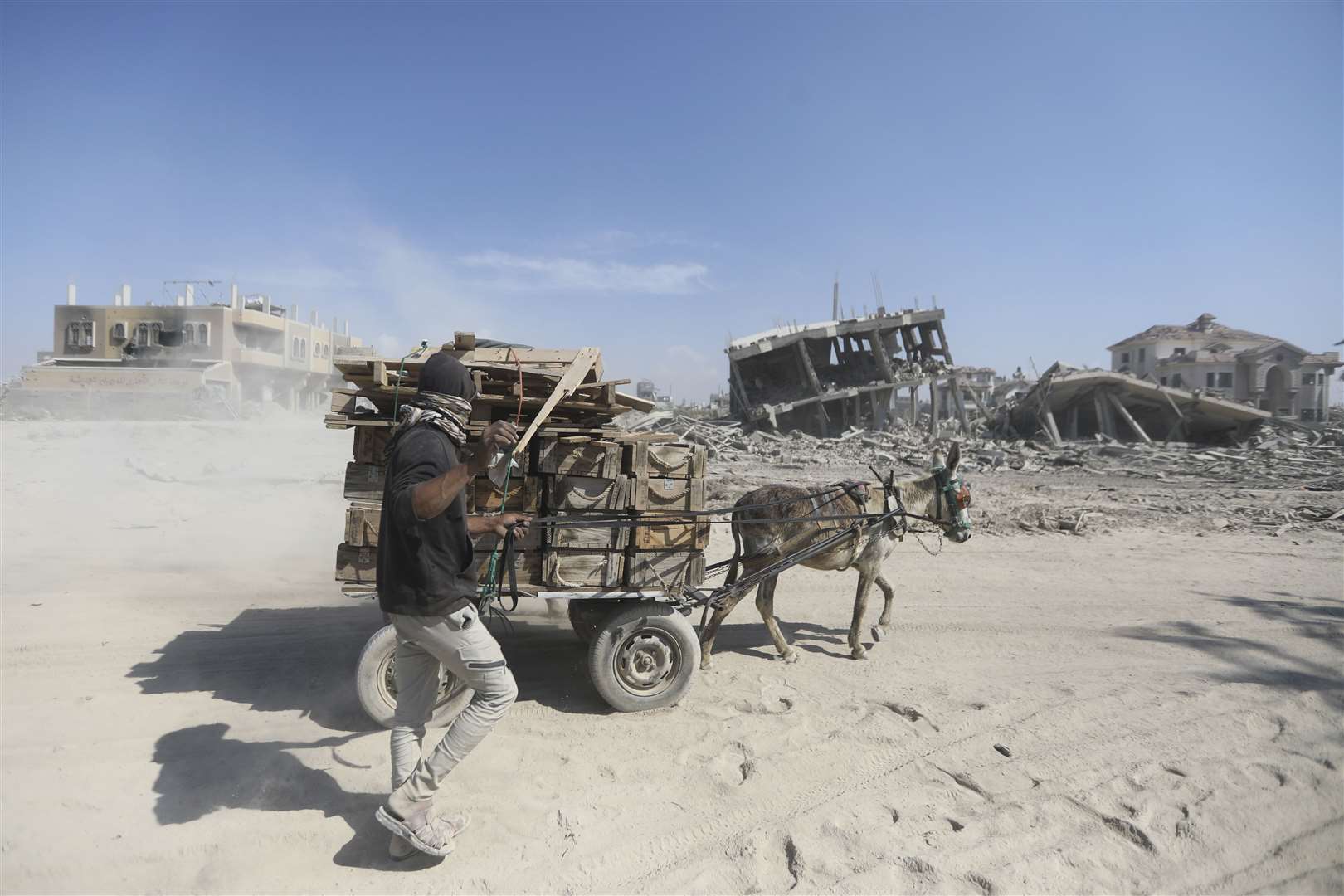 Palestinians walk through the destruction left by the Israeli air and ground offensive after they withdrew from Khan Younis in the southern Gaza Strip (Ismael Abu Dayyah/AP)