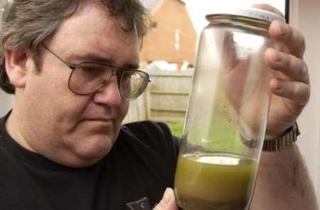 Michael Adach with a sample of the foul water from his garden. Picture: ANDY PAYTON