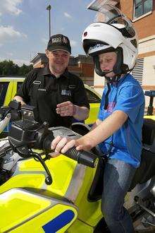 PC Mark Sutton talks hero Reece McGhee through the BMW motorcycle used by Kent Police