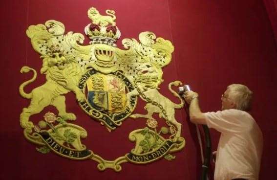 A restorer tends to the Royal Coat of Arms in Buckingham Palace’s ballroom (PA)