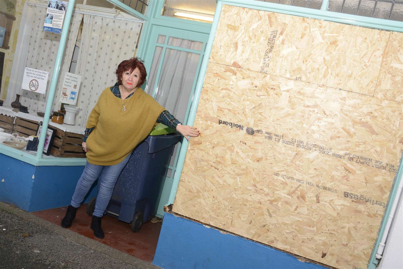 Janine Samuels with the smashed window boarded up at charity shop Relate. Picture: Paul Amos